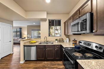 A modern kitchen with dark wood cabinets and stainless steel appliances.